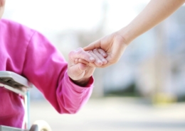 a younger person holding the hand of an elderly on a wheelchair